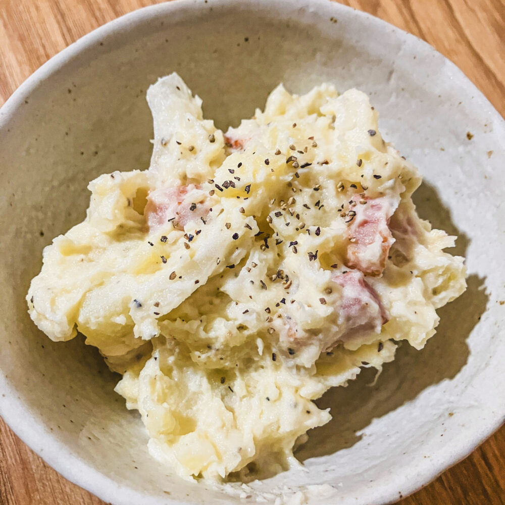 白い器に盛ったわが家のポテトサラダ。ベーコン入りで黒こしょうをふってある