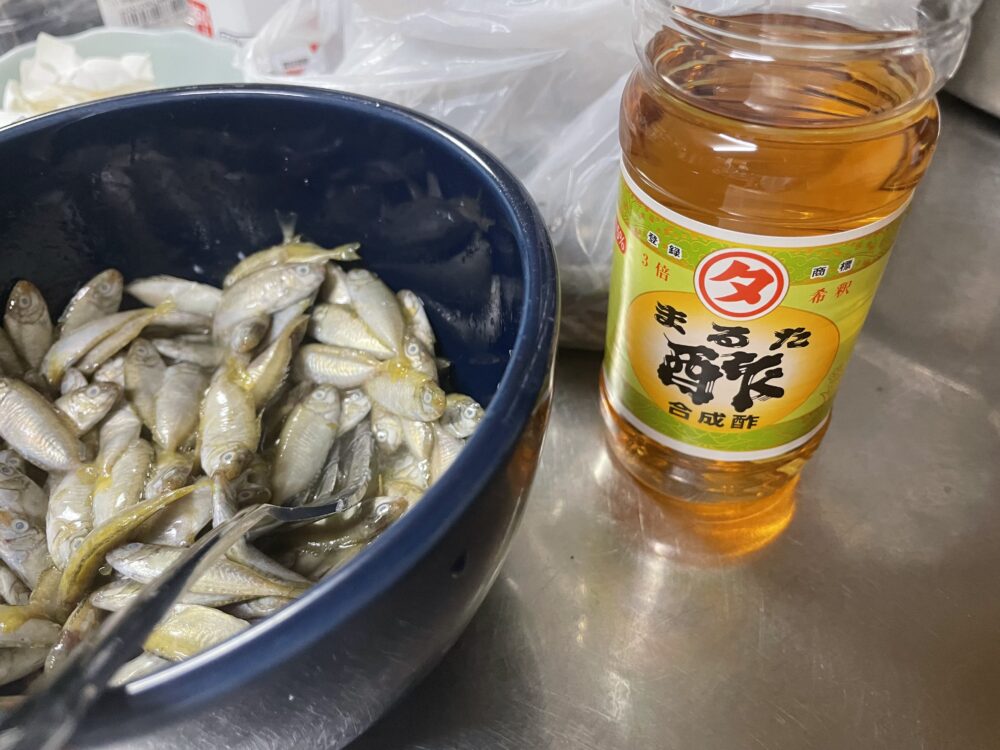 青いボウルに入れた生のスクと、その横に置いたまるた酢のボトル