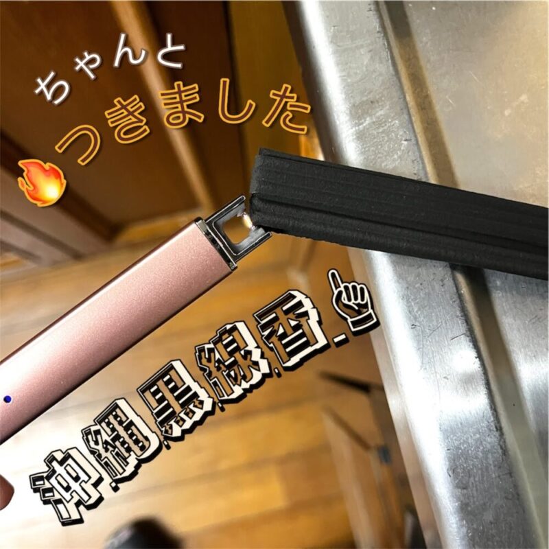 沖縄の黒線香(ヒラウコー)1枚の先に、ピンク色の電子ライターで火をつけているところ。線香の横に線が何本も入っている