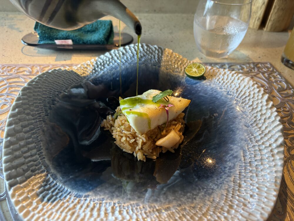 Nocturne Okinawaの魚料理に、目の前で緑色のソースをかけているところ
